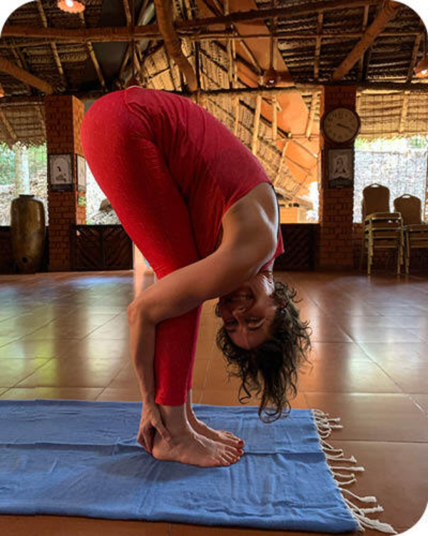 Kvinne gjør padangusthasan i India i rød yogadrakt, reise til Kerela