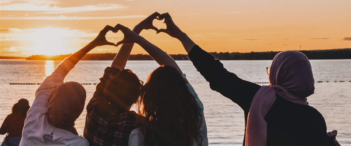 <p>Bilde av 4 kvinner i solnedgang som lager hjerter med hennende. Viljareiser personvern</p>