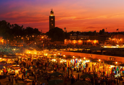 <p>Marrakech i Solnedgang. Moske i sort siluett og rød himmel i bakgrunn, markedsplass i front</p>