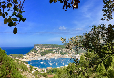 Utsiktsbilde over en bukt på Mallorca. Grønn vegetasjon rammer inn den blå himmelen og sjøen. Foto.