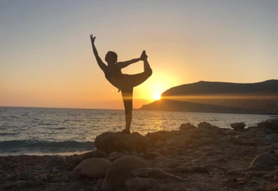 Kvinne som gjør yoga på stranden i Hellas Karpathos i solnedgang. 