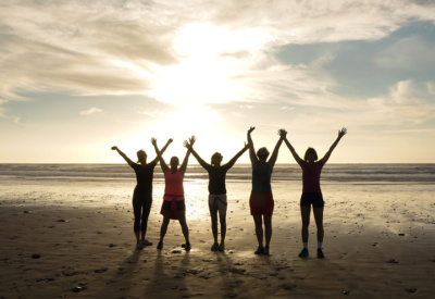 6 kvinner i siluett på strand i Agadir, hopper lett i solnedgang