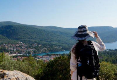 <p>En dame med sommerhatt og ryggsekk står oppe på fjellet og ser på utsikten over Stari Grad i Kroatia.</p>