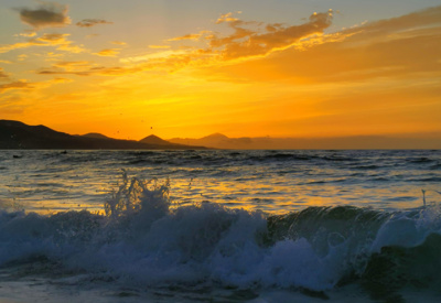 <p>Solnedgang med oransje himmel på stranden.</p>