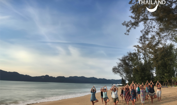 En gruppe damer som gjør qigong på strand i Thailand.