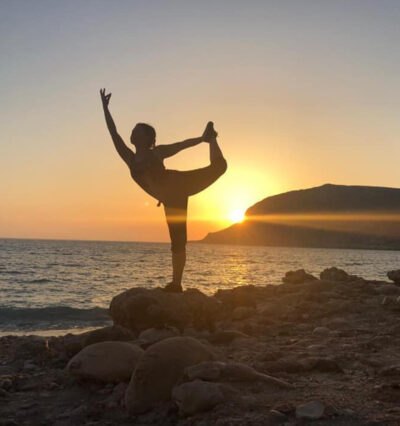 Kvinne som gjør yoga på stranden i Hellas Karpathos i solnedgang. 